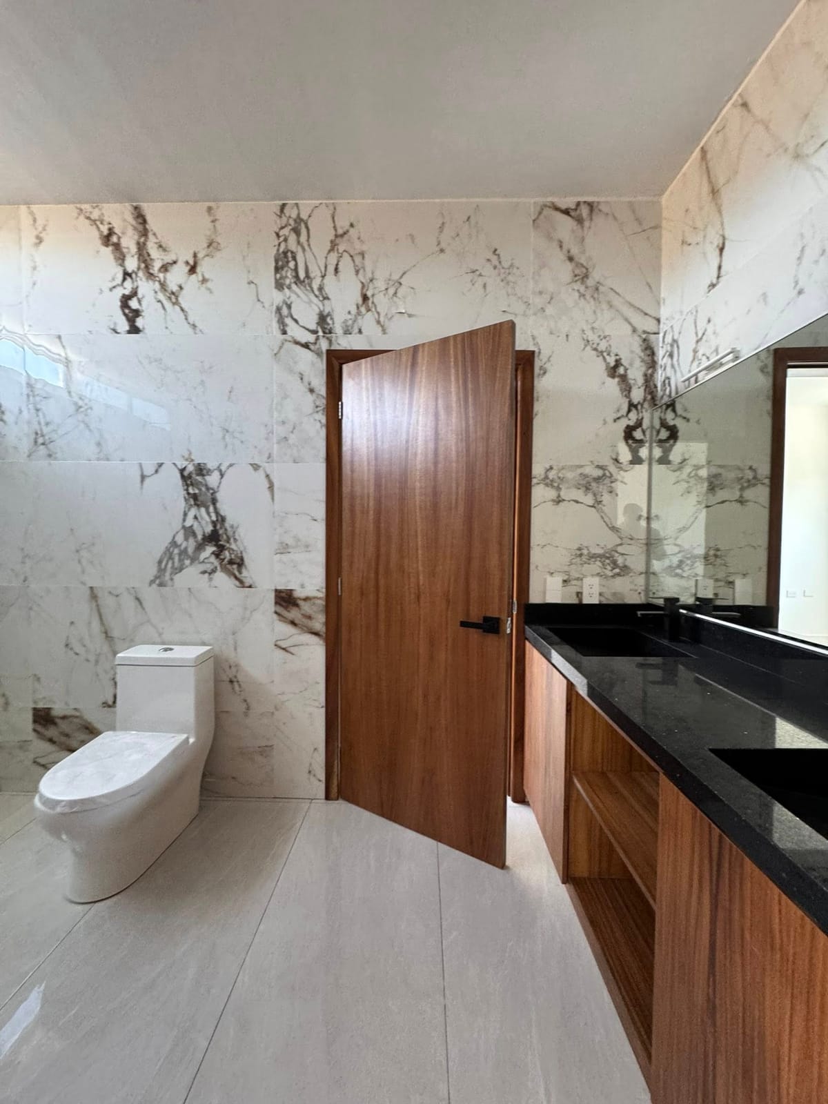 Baño con muros de mármol y doble lavamanos