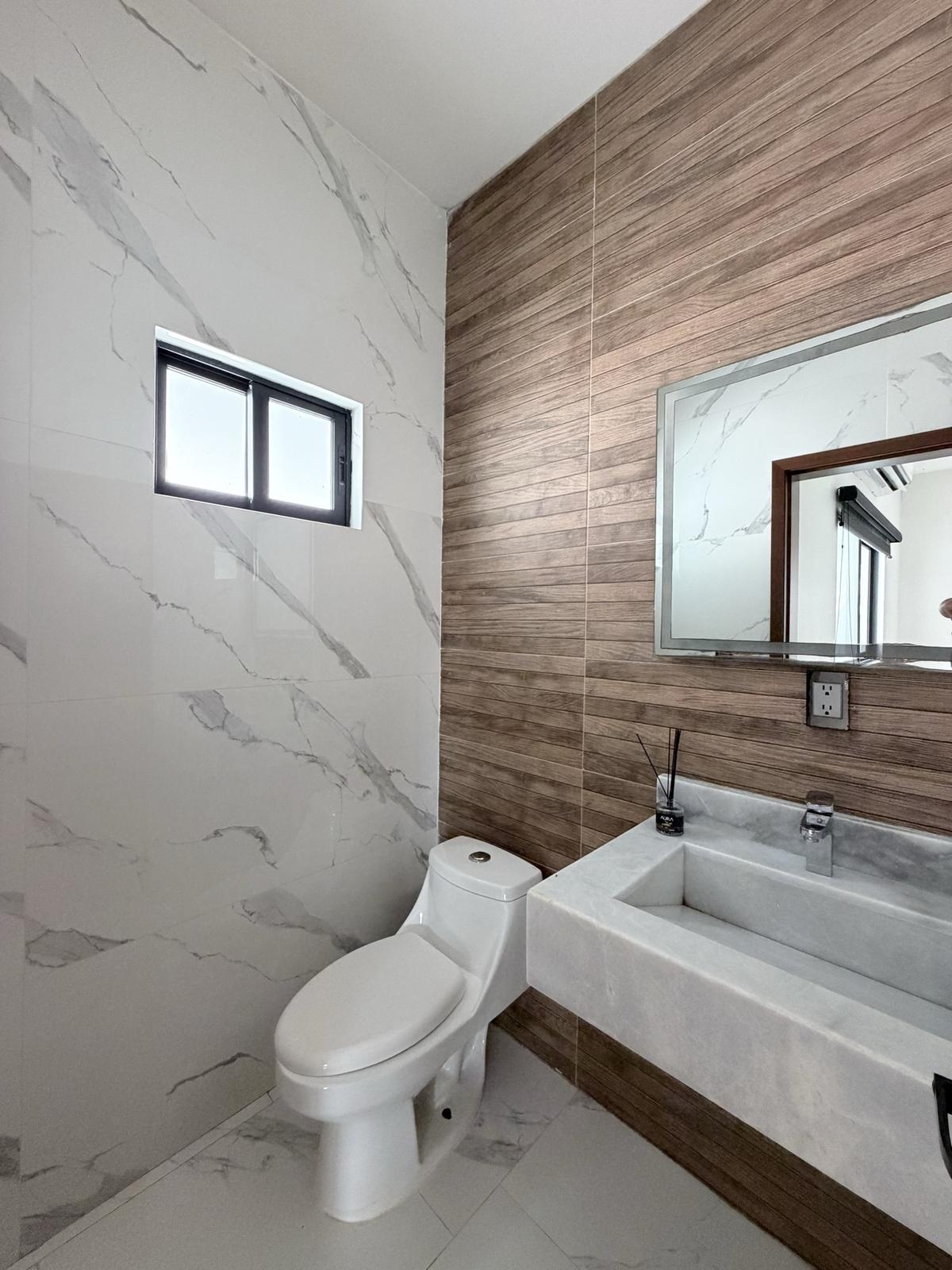 Medio baño de visita con muro de porcelanato tipo madera en casa en renta en Cerritos