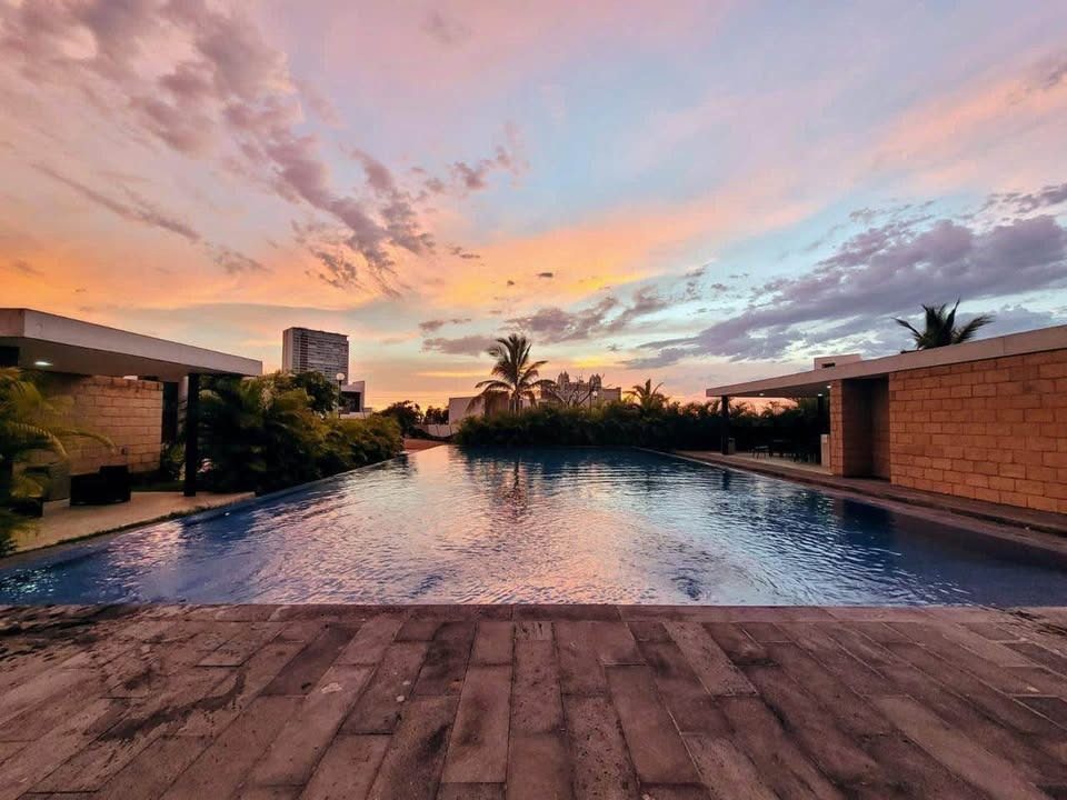 Alberca al atardecer con deck de madera en Soles Parque Residencial, Cerritos