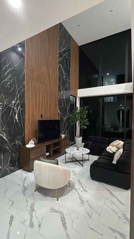 Sala con muro de mármol negro y lambrín de madera en casa en venta en Soles, Cerritos