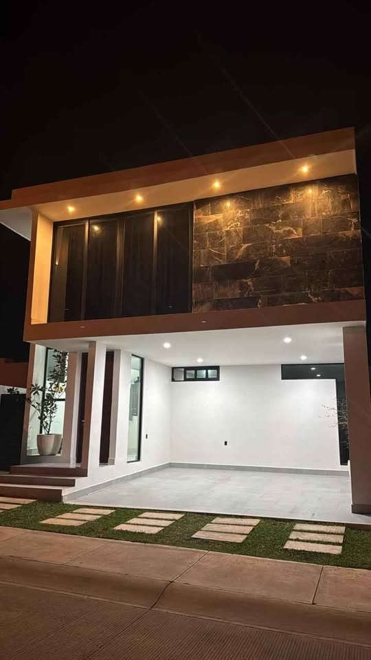 Fachada iluminada de noche con cochera techada en casa en venta en Soles Parque Residencial