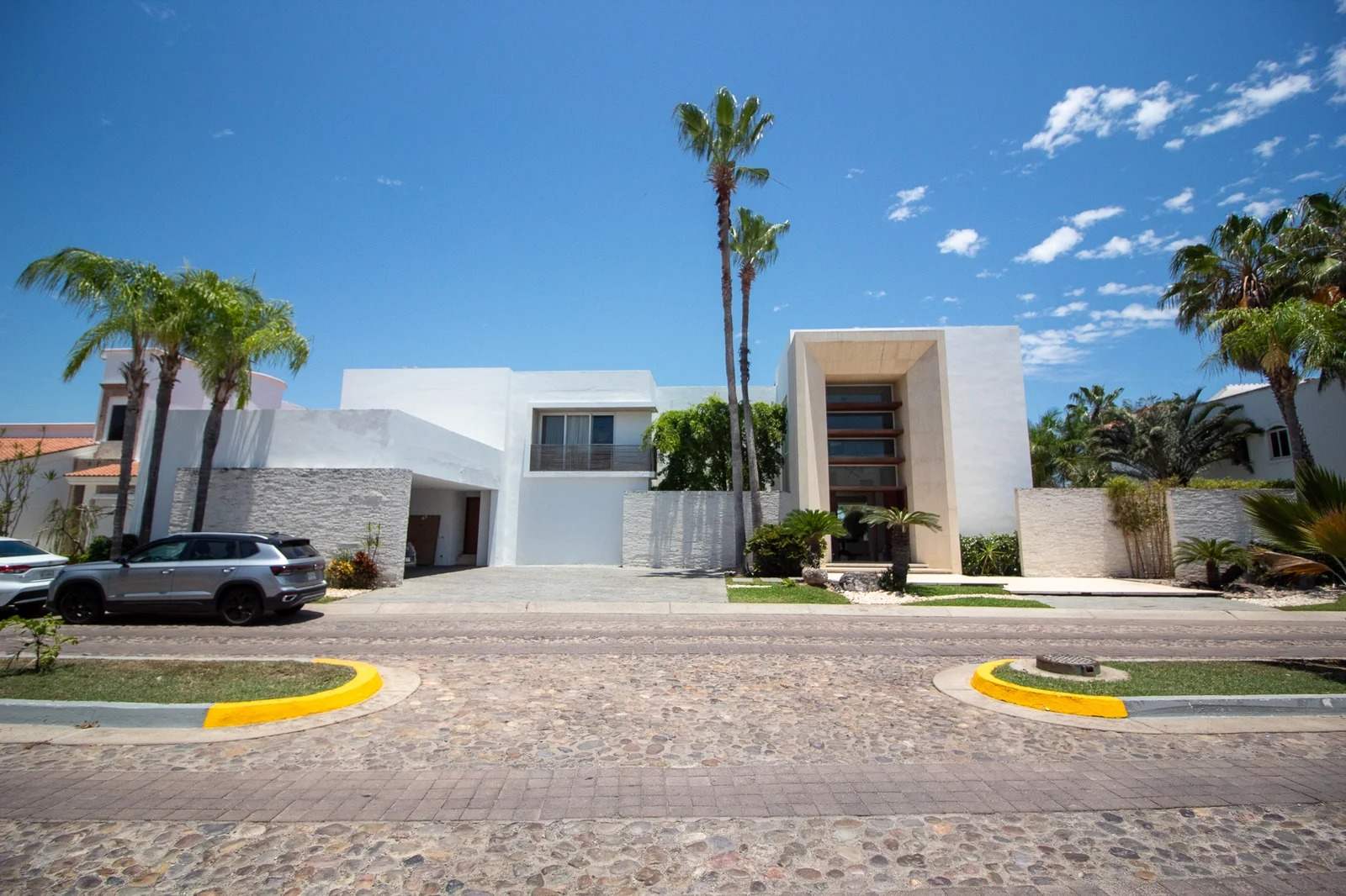 Fachada de la residencia en venta en El Cid, Mazatlán, rodeada de palmeras