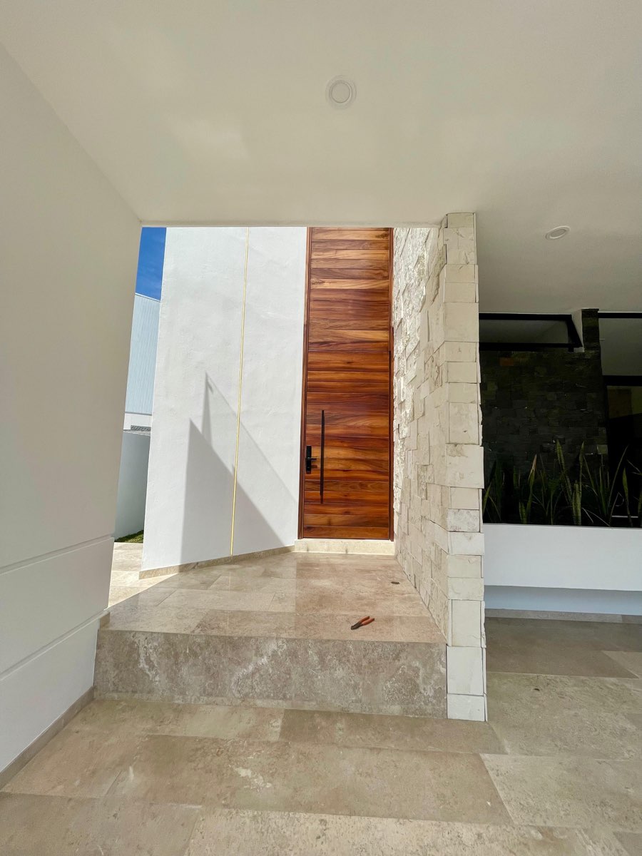 Puerta principal de madera con muro de cantera y piso de mármol en casa en venta en Mazatlán