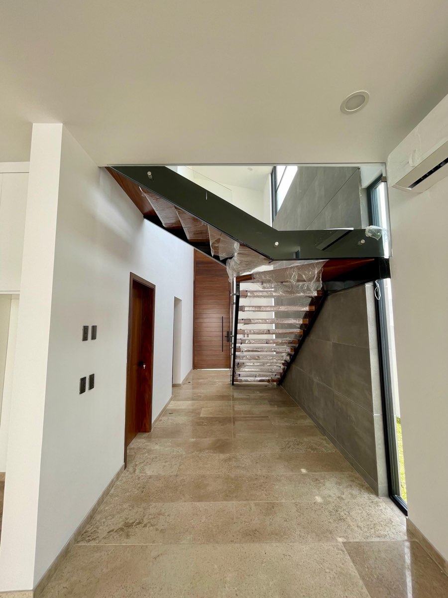 Pasillo de planta baja con piso de mármol hacia la escalera en casa en venta en Mazatlán