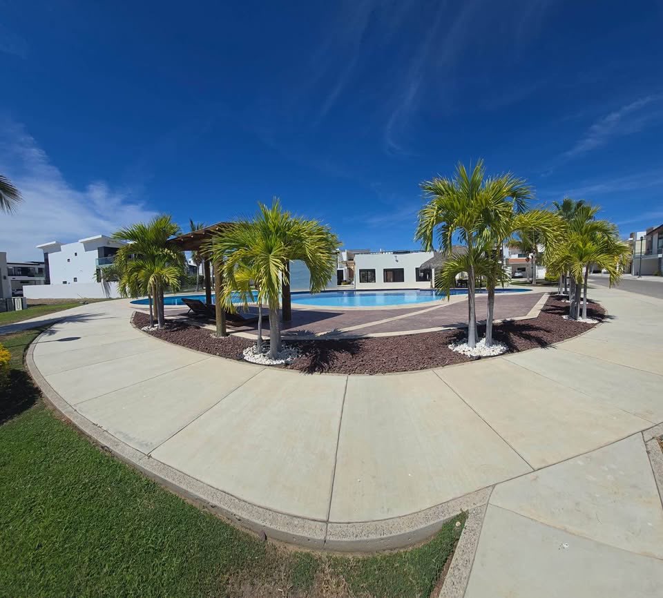 Alberca común con palmeras y palapa del residencial Paraíso Marina en Mazatlán