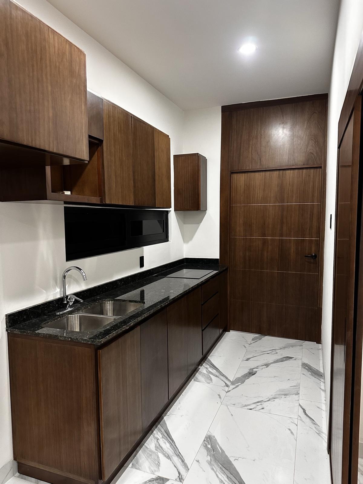Cocina equipada con alacenas de madera y cubierta de granito negro en Vilanova 306, Mazatlán