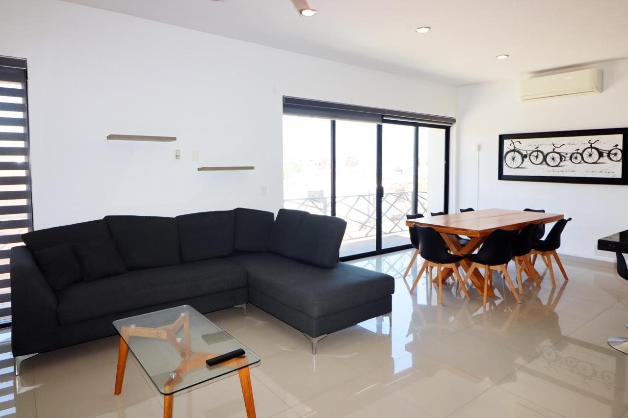 Sala con sofá seccional y comedor en departamento en venta en Playa Sur, Mazatlán
