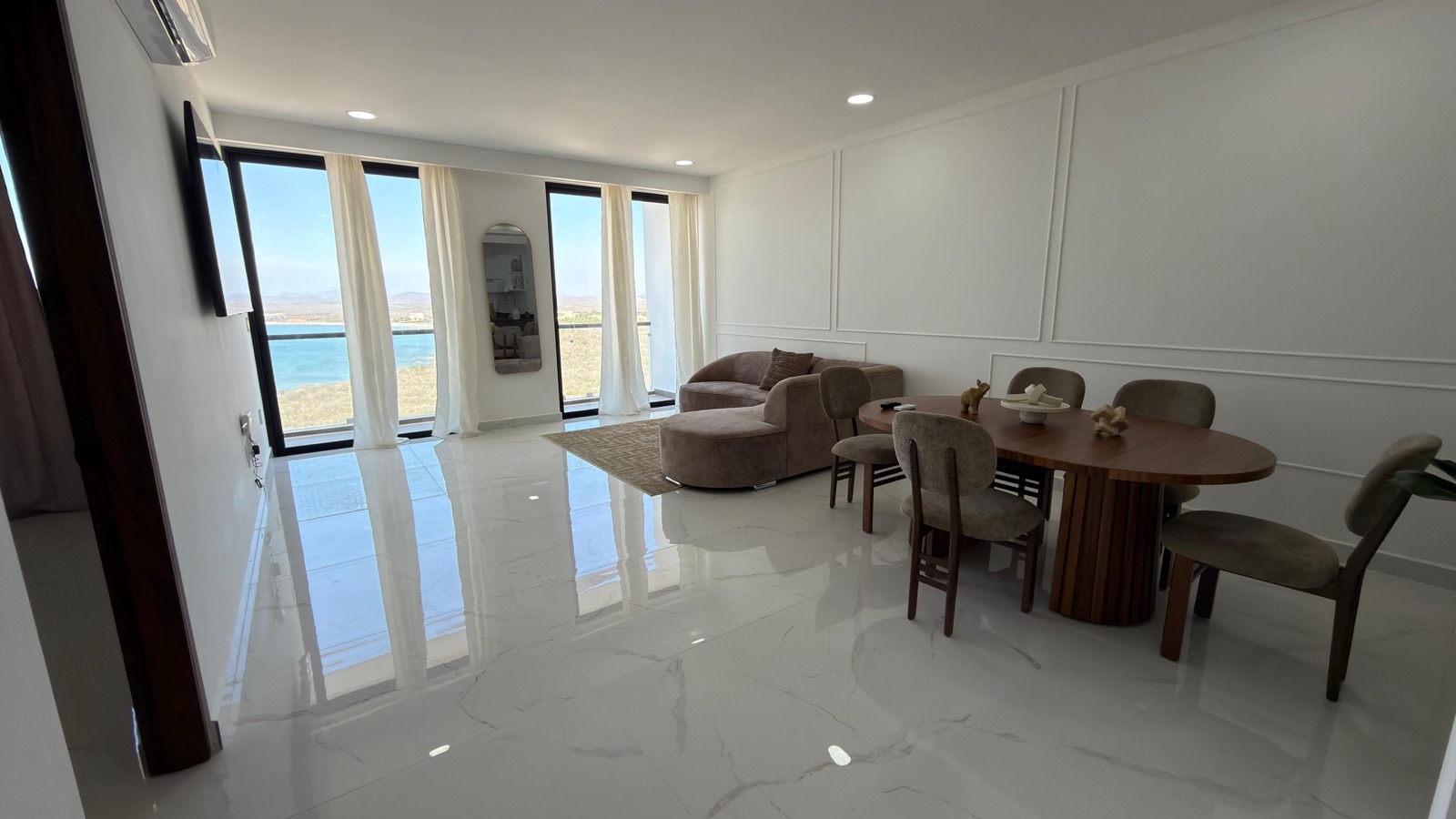 Sala y comedor amueblados con ventanal y vista al mar en departamento en venta en Mazatlán, Grand Sunset