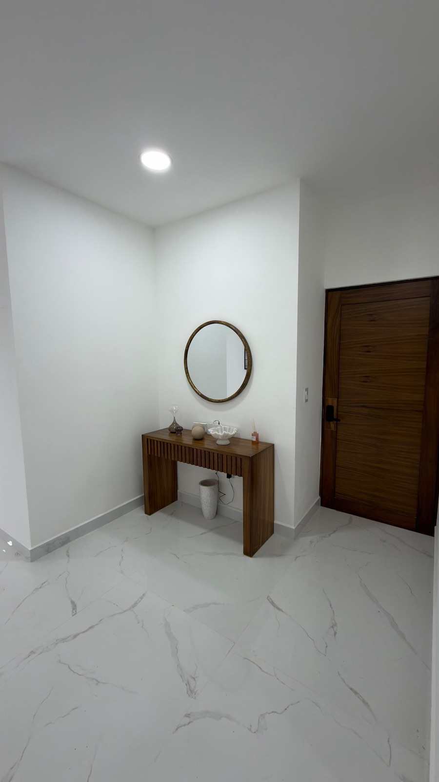 Recibidor con consola de madera y espejo redondo en departamento en venta en Mazatlán