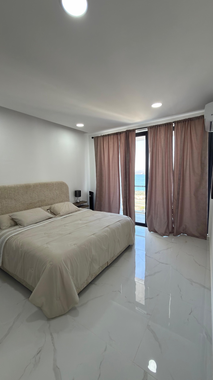 Recámara principal con cama king y balcón con vista al mar en departamento en venta en Mazatlán