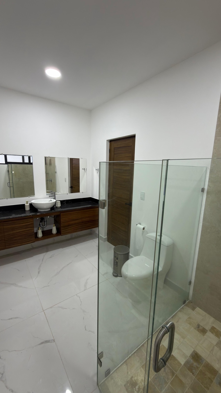 Baño principal amplio con regadera de cristal y lavabo sobre mueble de madera en Mazatlán