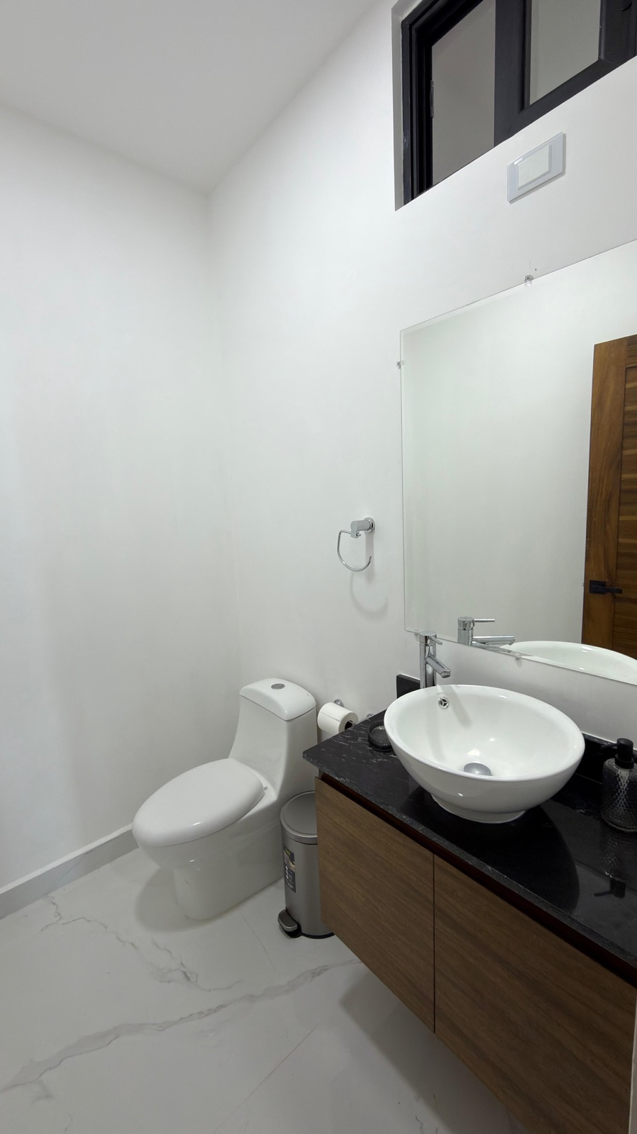 Medio baño de visita con lavabo de madera y espejo en departamento en venta en Mazatlán