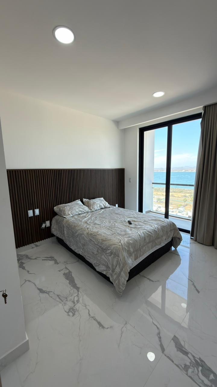 Recámara principal con cabecera de madera y ventanal con vista al mar en Mazatlán