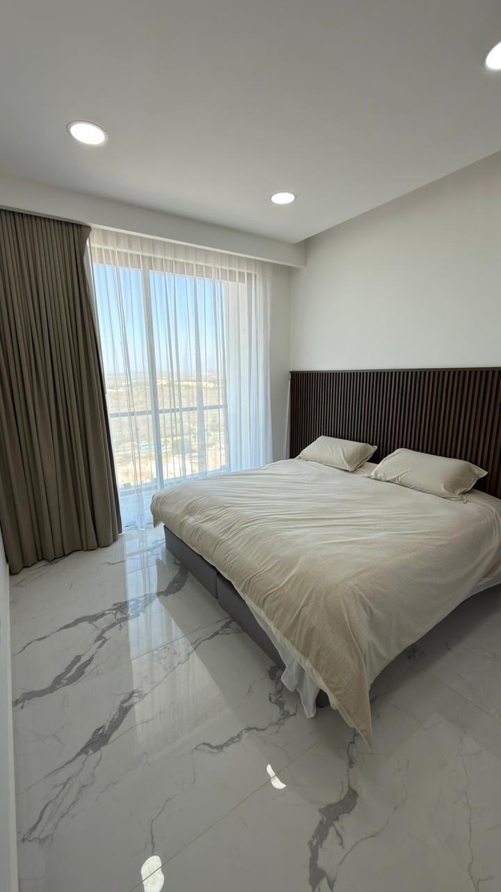 Recámara con cama king y ventanal con cortinas en departamento frente al mar en Mazatlán