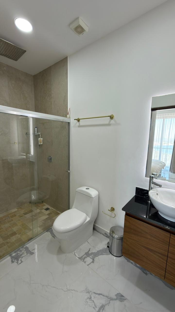 Baño completo con regadera de cristal y lavabo sobre mueble de madera en Playa Brujas, Mazatlán