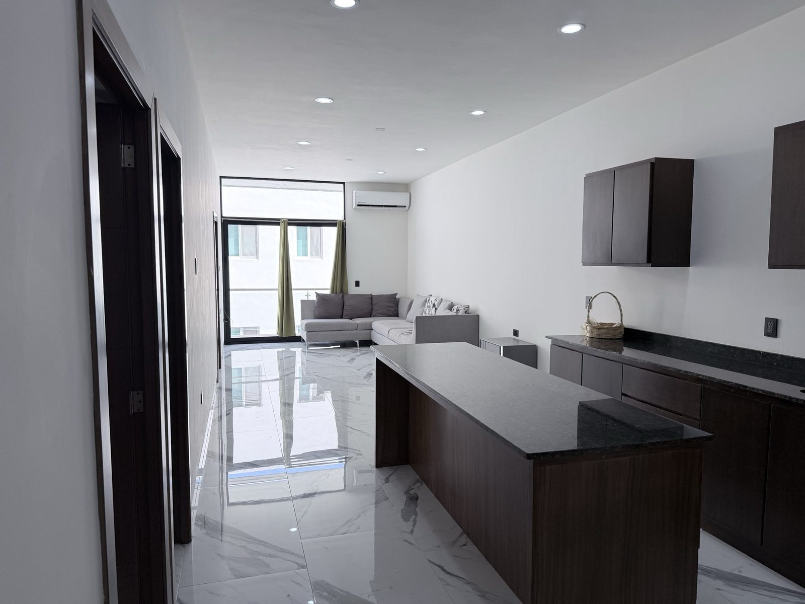 Sala, comedor y cocina integrados con ventanal en departamento en venta en Sábalo Country