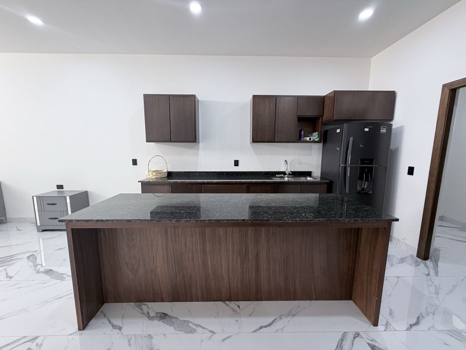 Cocina equipada con isla, cubierta de granito y alacenas de madera en Vilanova, Mazatlán