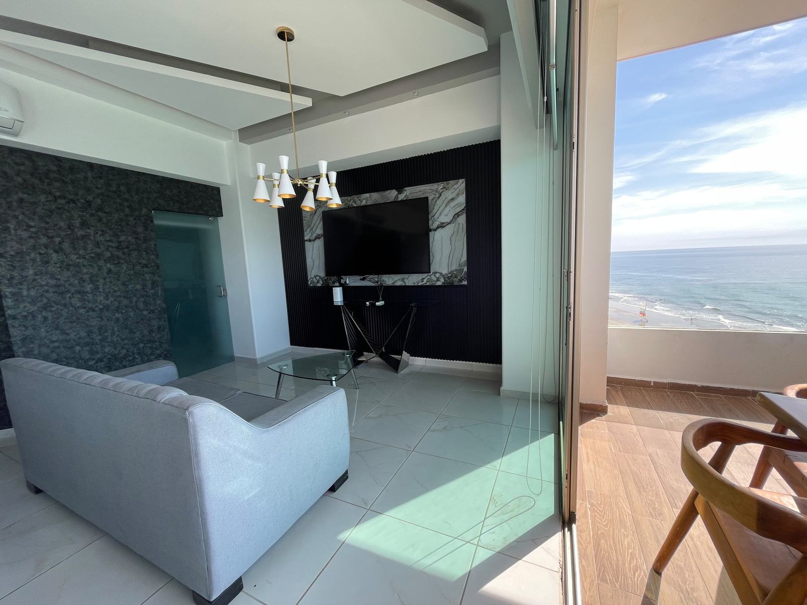 Estancia con pantalla y salida al balcón en departamento a pie de playa en Mazatlán